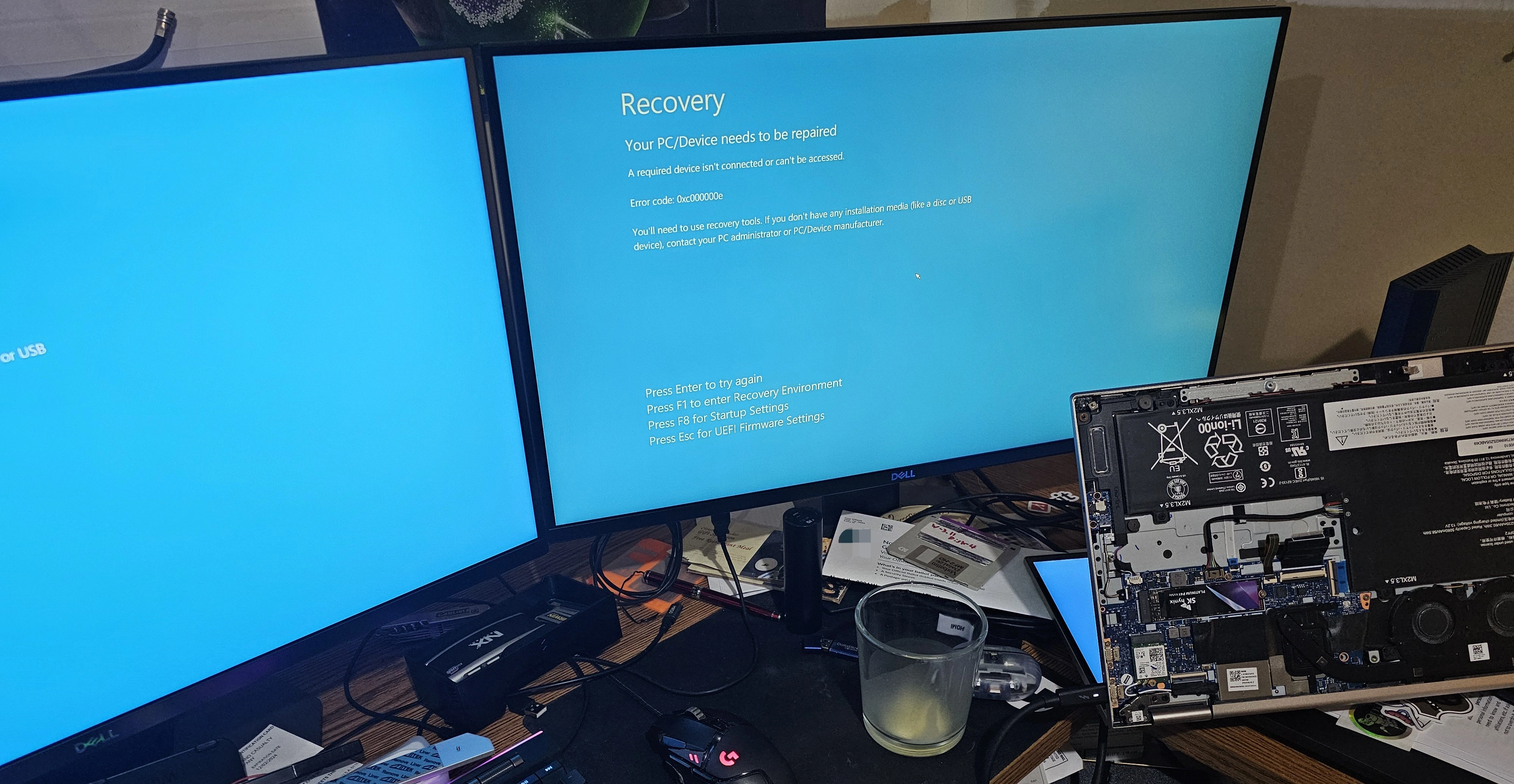 Windows Recovery screen on external monitors. Laptop is lying on its screen,
with the bottom cover removed exposing the
internals.